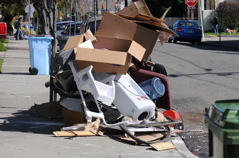 A pile of cardboard boxes, an armchair and other discarded household items left at the curb on a residential street
